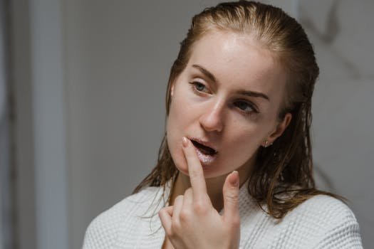 Adult woman applying a lip scrub as part of her beauty routine indoors.